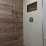 Inloopdouche met houten wandtegels en een moderne inbouwkraan, inclusief een ingebouwde nis voor opslag.