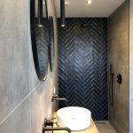 Moderne badkamer met een witte waskom, zwart-witte accenten en een visgraad patroon op de muur van de inloopdouche.