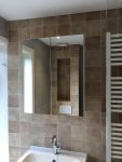 Badkamer met klassieke wandtegels in bruintinten, een grote spiegel, en een design handdoekradiator, passend bij de sfeer van een jaren '30 woning.