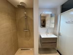 Badkamer met inloopdouche met regenwoud douchekop, houten wastafelmeubel en strakke, eigentijdse afwerking.
