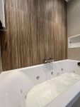 Luxe badkamer met een jacuzzi, afgewerkt met houten wandtegels voor een warme, moderne uitstraling.