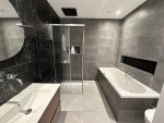 Luxe badkamer met inloopdouche, vrijstaand bad, dubbele wastafel en marmeren wandtegels voor een elegante uitstraling.