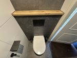 Volledig afgewerkte toiletruimte met zwevend wandcloset, zwarte accessoires en houten planchet in Groenekan