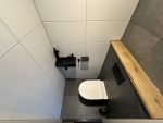 toilet rnovatie 23 Modern wandcloset met zwarte bedieningsplaat en houtaccent boven tegelombouw in toilet renovatie Groenekan